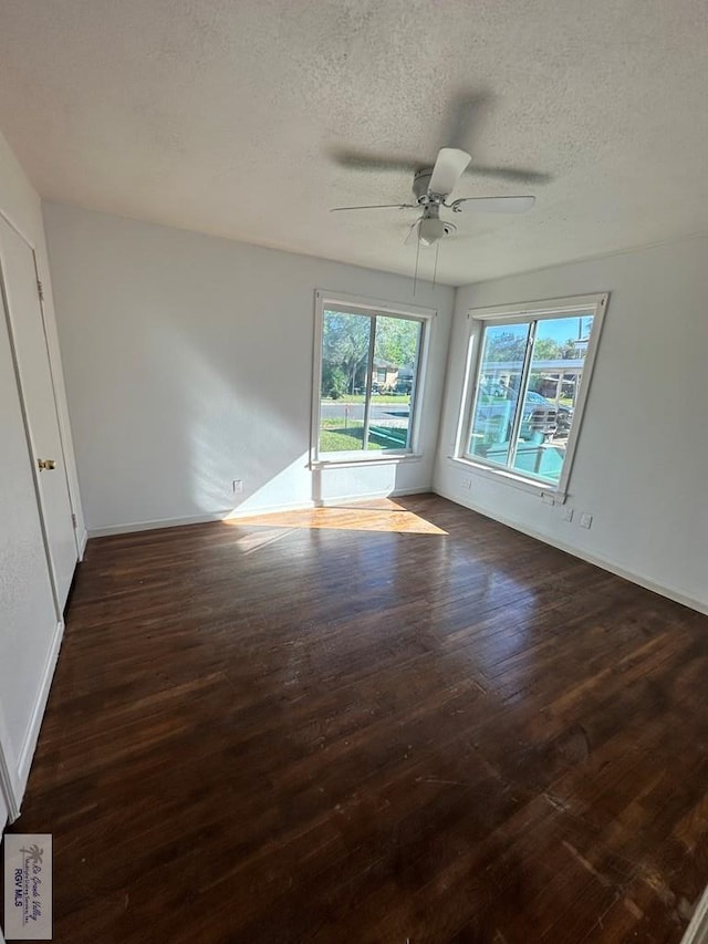 empty room featuring ceiling fan, dark wood-type flooring, and a textured ceiling