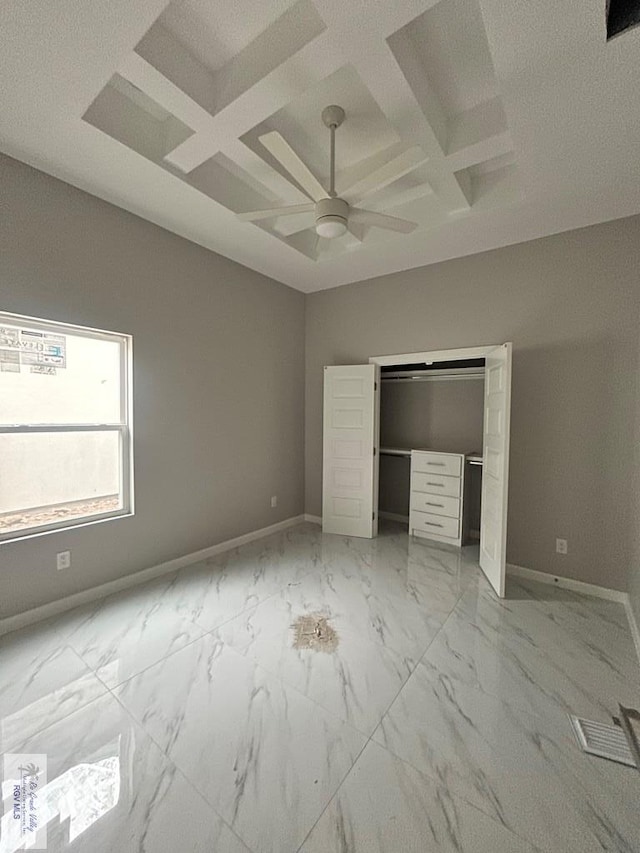 unfurnished bedroom with ceiling fan, coffered ceiling, and a closet