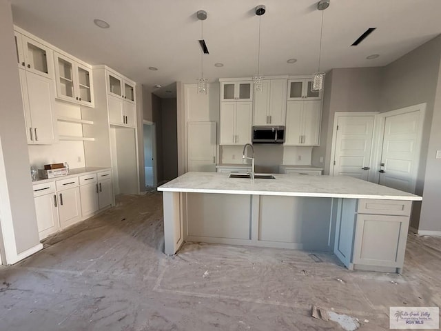 kitchen featuring pendant lighting, sink, white cabinets, and a large island with sink