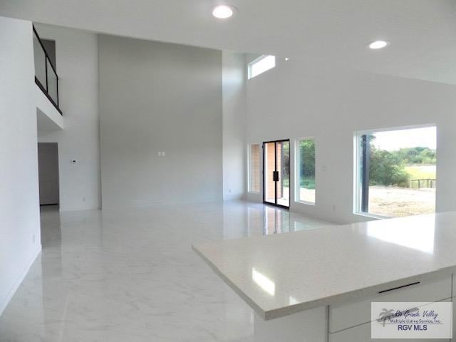 kitchen with white cabinetry and high vaulted ceiling