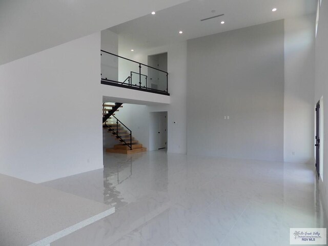 unfurnished living room featuring a towering ceiling