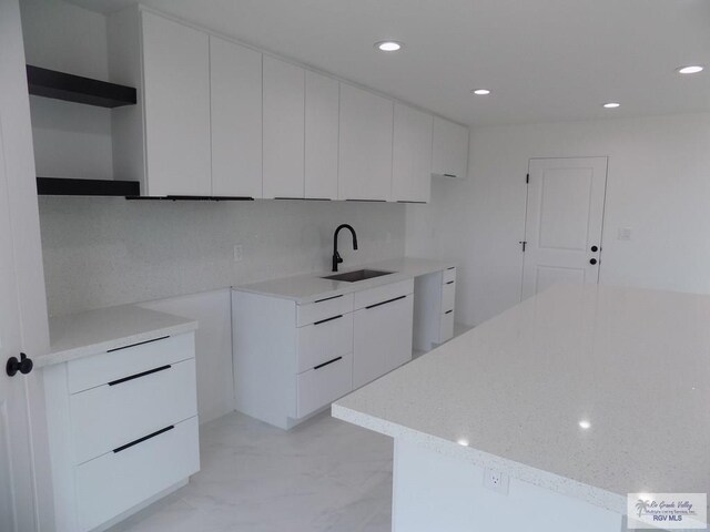 kitchen featuring backsplash, white cabinetry, and sink