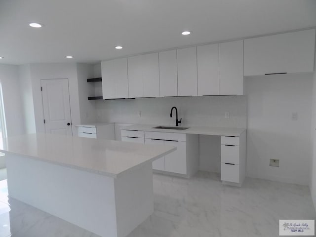 kitchen with decorative backsplash, a center island, white cabinetry, and sink