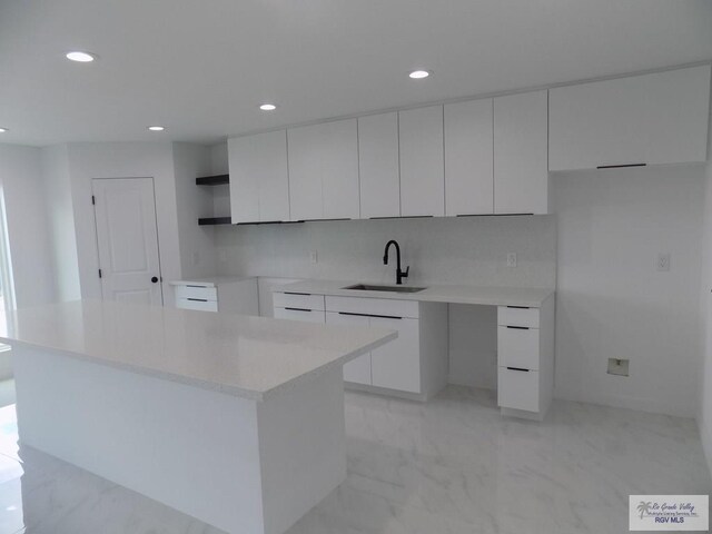 kitchen with a kitchen island, white cabinetry, sink, and tasteful backsplash