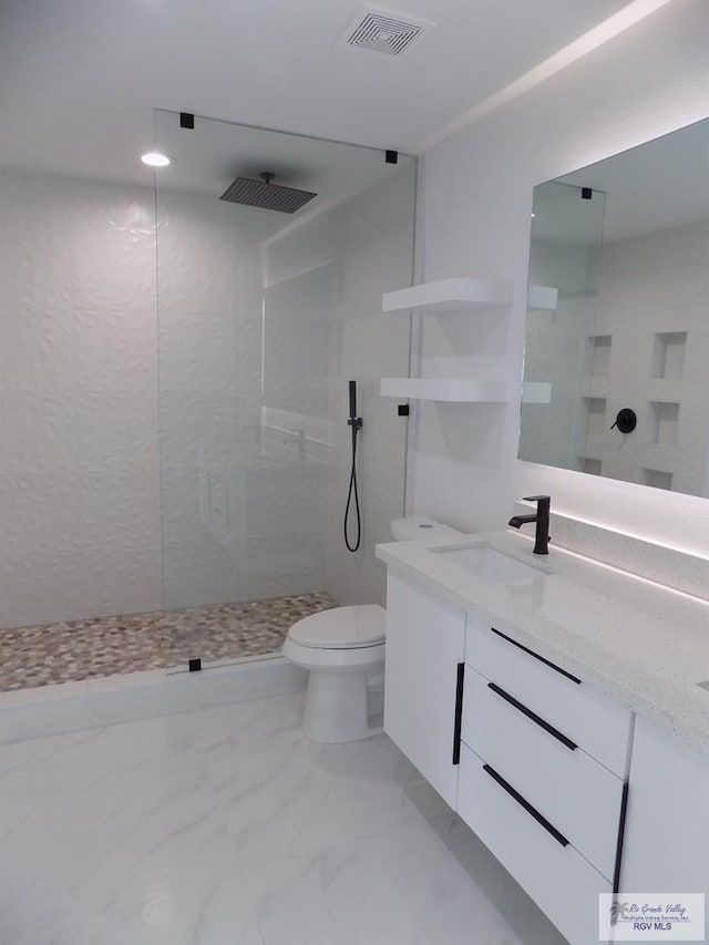 bathroom with tiled shower, vanity, and toilet