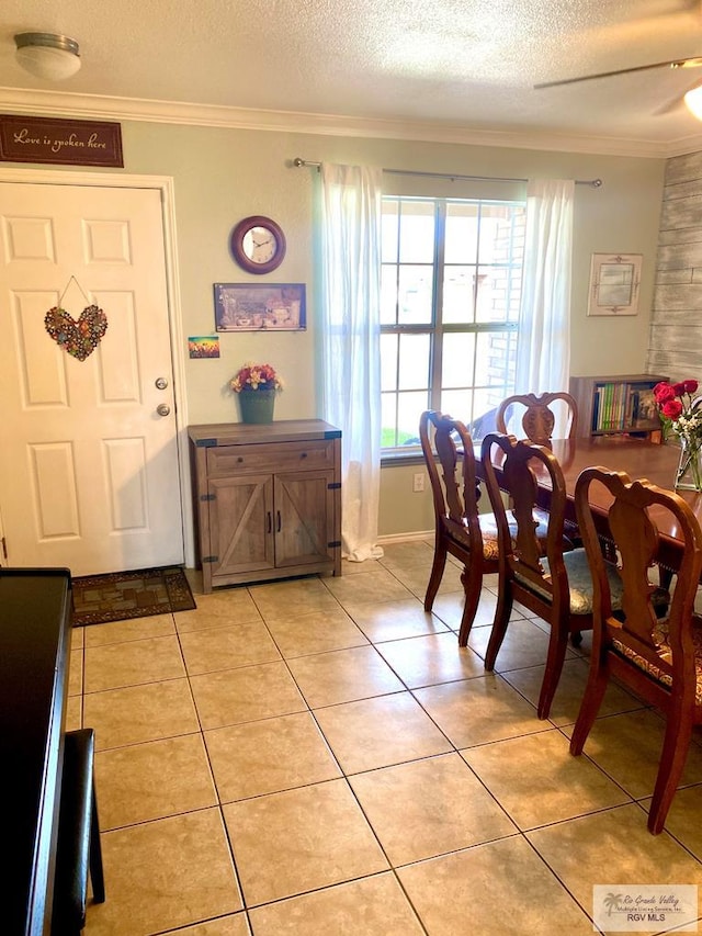 tiled dining area featuring a textured ceiling, crown molding, and ceiling fan