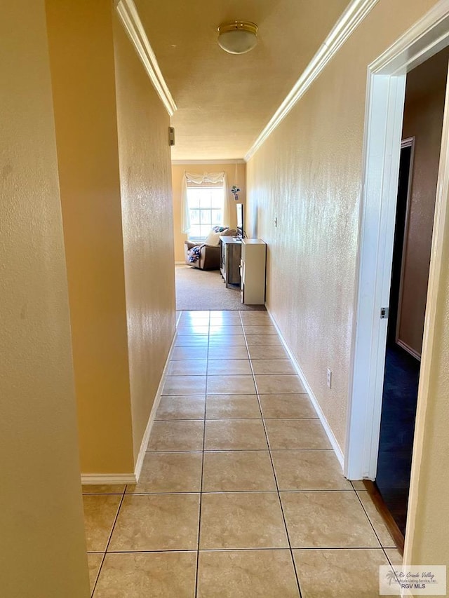 hallway featuring ornamental molding and light tile patterned flooring