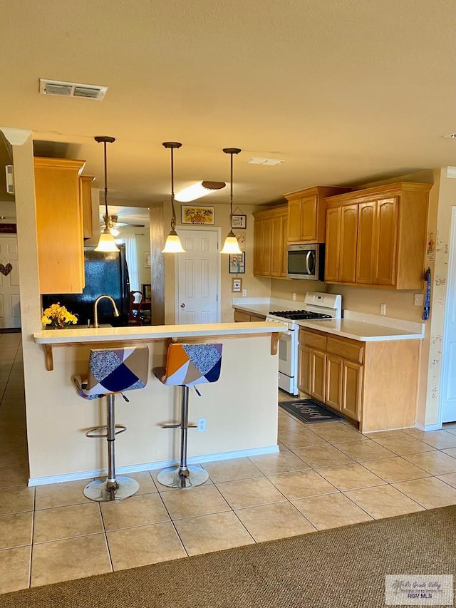 kitchen with decorative light fixtures, light tile patterned flooring, a breakfast bar, white range with gas cooktop, and kitchen peninsula