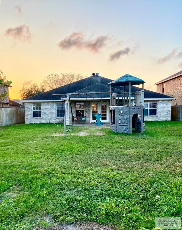 back house at dusk with a lawn and a gazebo