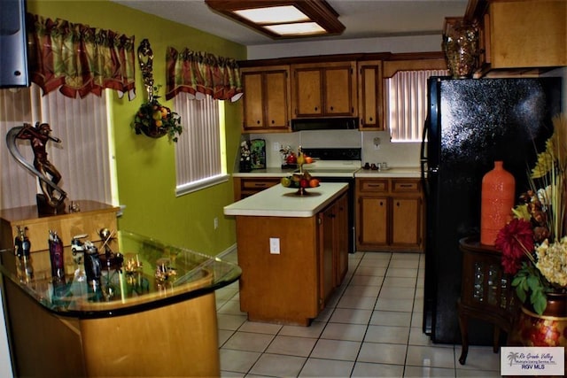 kitchen with a center island, light tile patterned flooring, black refrigerator, and extractor fan