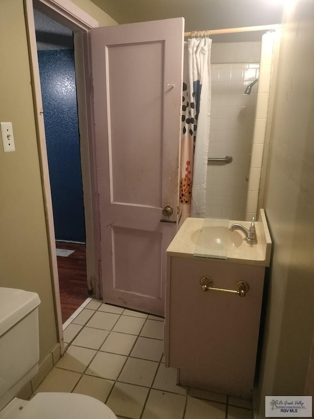 bathroom featuring toilet, vanity, a shower with shower curtain, and tile patterned floors