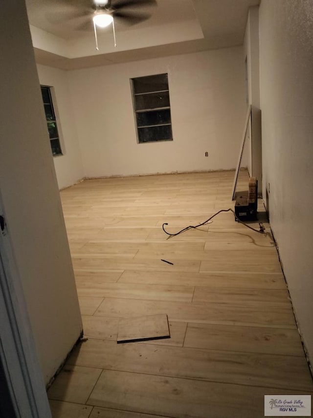 empty room featuring a tray ceiling and light hardwood / wood-style flooring