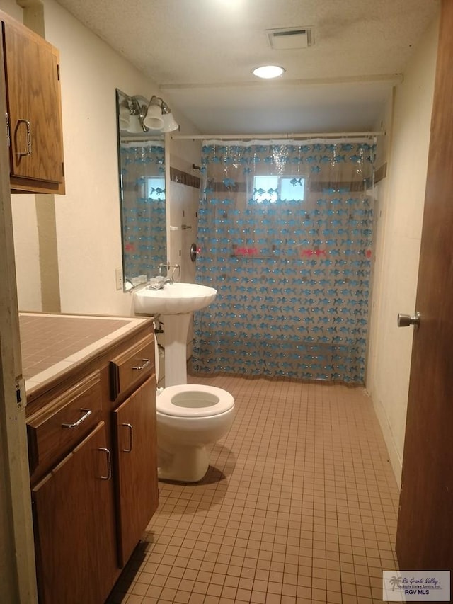 bathroom with tile patterned flooring, toilet, and curtained shower