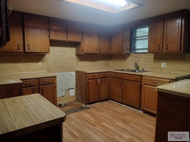 kitchen featuring decorative backsplash, light hardwood / wood-style floors, and sink