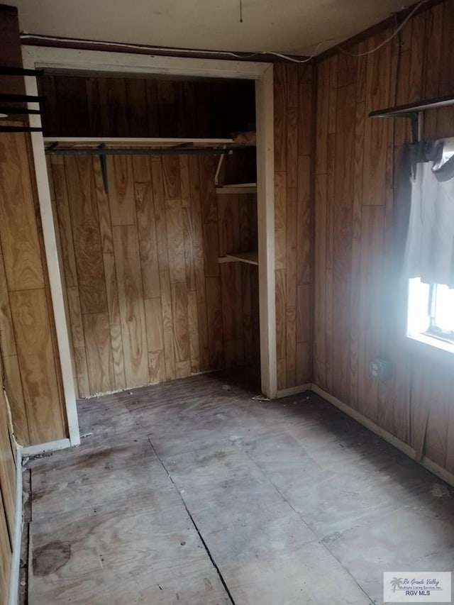 unfurnished bedroom with a closet and wood walls