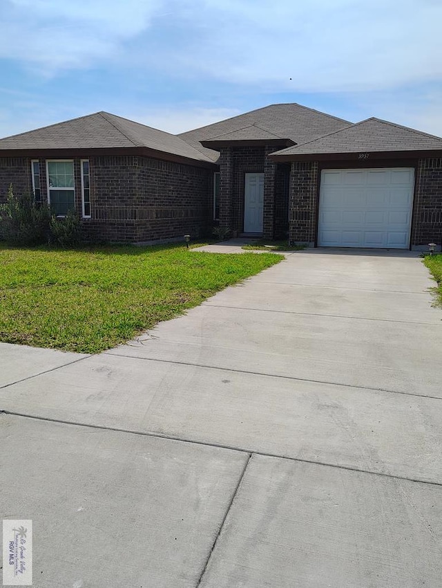 3937 Oak Valley Dr, Brownsville, TX 78520 - view of front of home with concrete driveway, a garage, brick siding, and a front yard