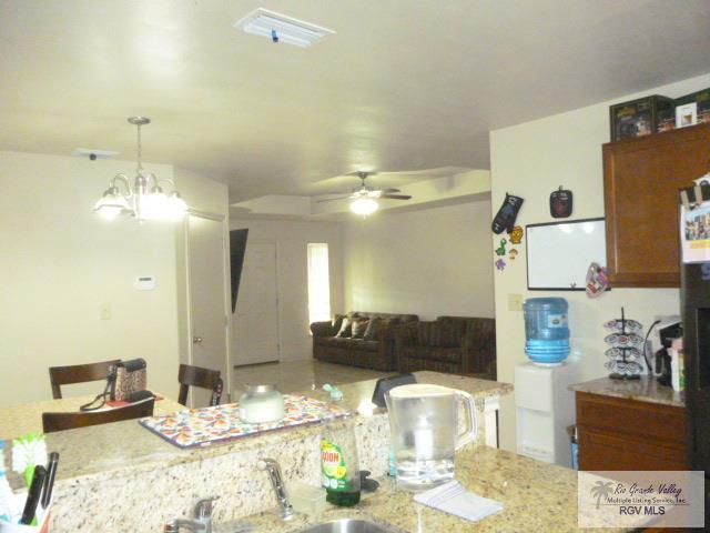 3937 Oak Valley Dr, Brownsville, TX 78520 - kitchen with a sink, a ceiling fan, decorative light fixtures, a chandelier, and brown cabinets