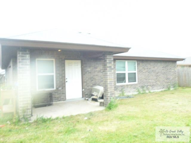 3937 Oak Valley Dr, Brownsville, TX 78520 - back of property with brick siding, a patio area, and a lawn