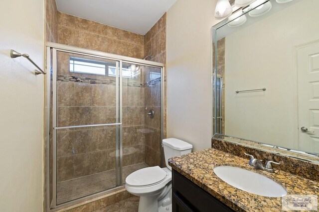 bathroom featuring vanity, toilet, and a shower with shower door