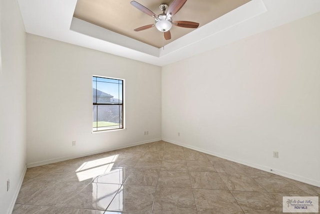 unfurnished room featuring ceiling fan and a raised ceiling