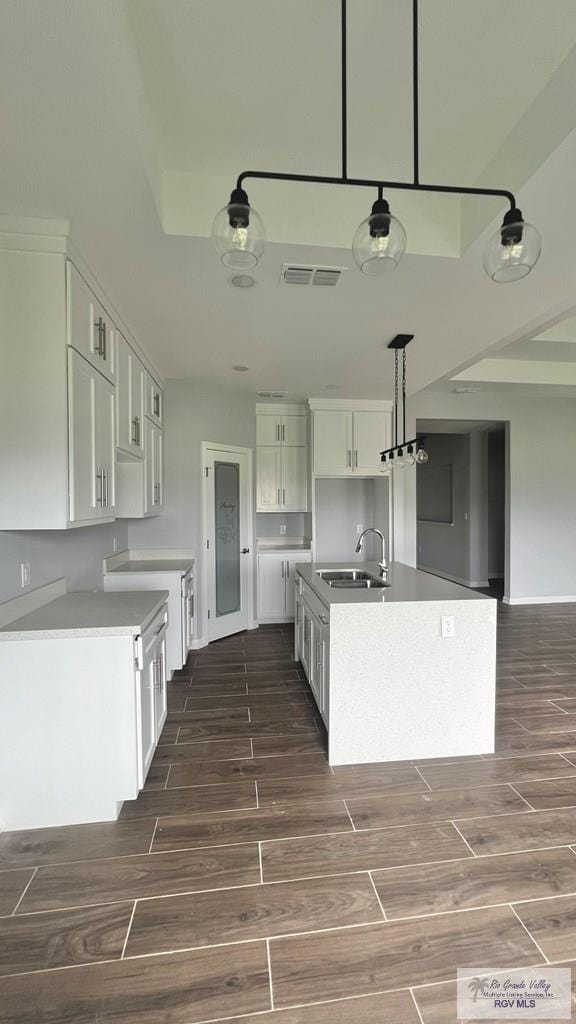 2517 S Christian Cir, Harlingen, TX 78550 - kitchen featuring dark wood-style floors, white cabinets, a center island with sink, and decorative light fixtures