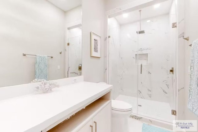 bathroom featuring vanity, a marble finish shower, and toilet
