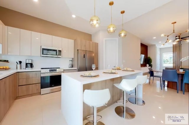 kitchen with light countertops, modern cabinets, a breakfast bar, and stainless steel appliances