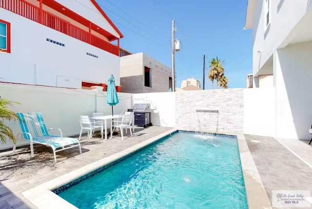 view of swimming pool with grilling area, a patio, a fenced in pool, and a fenced backyard