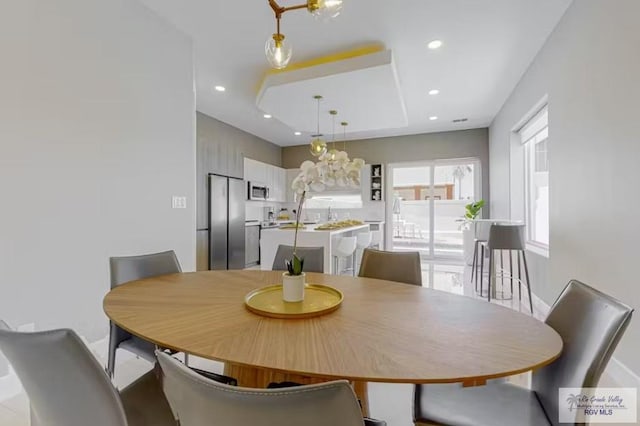 dining room with a raised ceiling, baseboards, and recessed lighting