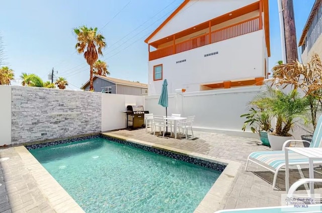 view of swimming pool with fence, outdoor dining space, grilling area, a fenced in pool, and a patio area