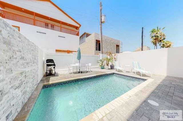 view of swimming pool featuring grilling area, a patio, a fenced in pool, and a fenced backyard
