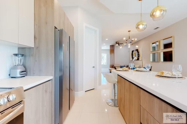 kitchen with decorative light fixtures, modern cabinets, light countertops, light tile patterned floors, and stainless steel appliances