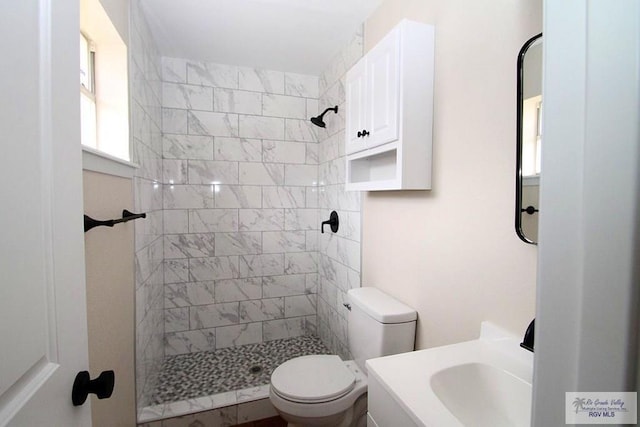 bathroom with vanity, tiled shower, and toilet