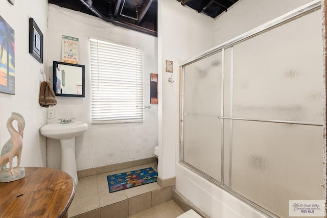 bathroom featuring tile patterned flooring, combined bath / shower with glass door, and toilet