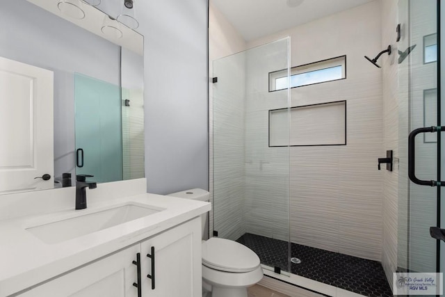 bathroom with vanity, toilet, and a shower with door