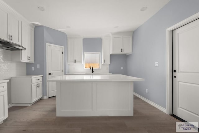 kitchen featuring a kitchen island, sink, white cabinets, and light hardwood / wood-style floors