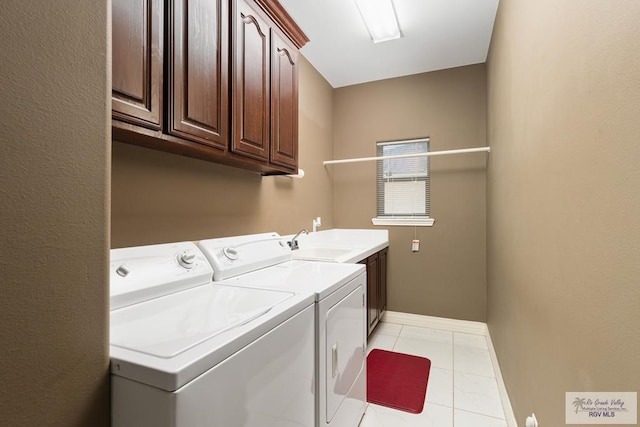 laundry area featuring light tile patterned floors, a sink, baseboards, cabinet space, and washer and clothes dryer