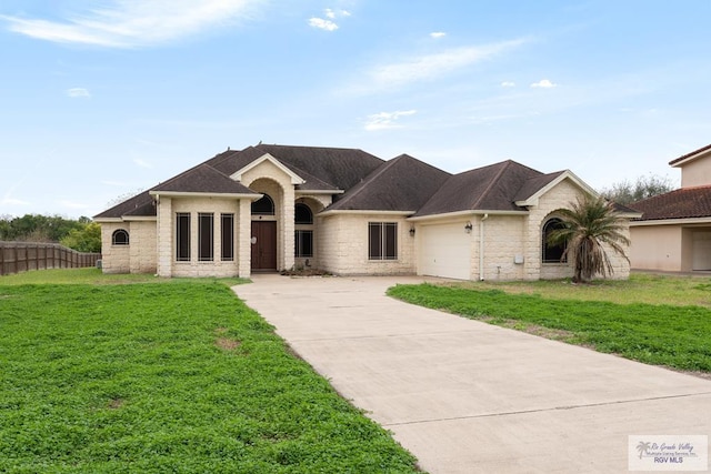 view of front of house with a garage, driveway, roof with shingles, fence, and a front lawn