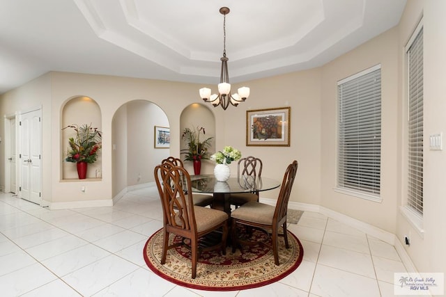 dining area featuring a chandelier, a tray ceiling, light tile patterned flooring, and baseboards