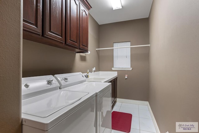 washroom with cabinet space, light tile patterned floors, baseboards, washer and clothes dryer, and a sink