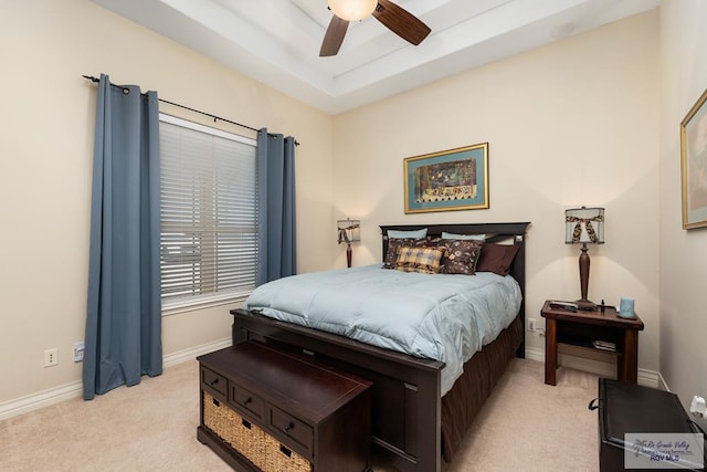 bedroom featuring light carpet, ceiling fan, baseboards, and a raised ceiling