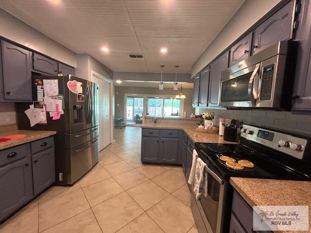 kitchen featuring tasteful backsplash, decorative light fixtures, light tile patterned floors, appliances with stainless steel finishes, and kitchen peninsula