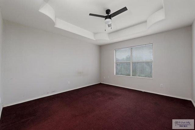 empty room featuring carpet floors, ceiling fan, and a raised ceiling