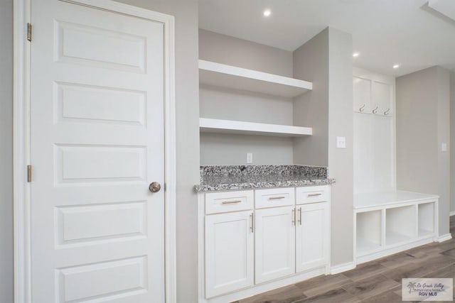 bar featuring hardwood / wood-style flooring, white cabinetry, and light stone counters