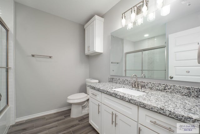 full bathroom with wood-type flooring, vanity, toilet, and bath / shower combo with glass door