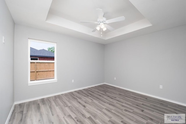 unfurnished room with a tray ceiling, ceiling fan, and hardwood / wood-style floors