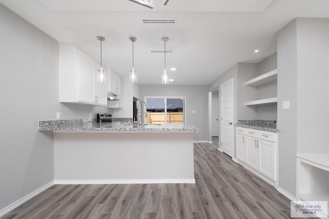 kitchen with decorative light fixtures, white cabinetry, kitchen peninsula, and light hardwood / wood-style flooring