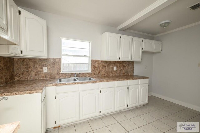 718 Pierce Ave, Harlingen, TX 78550 - kitchen with tasteful backsplash, light tile patterned flooring, white cabinetry, and crown molding