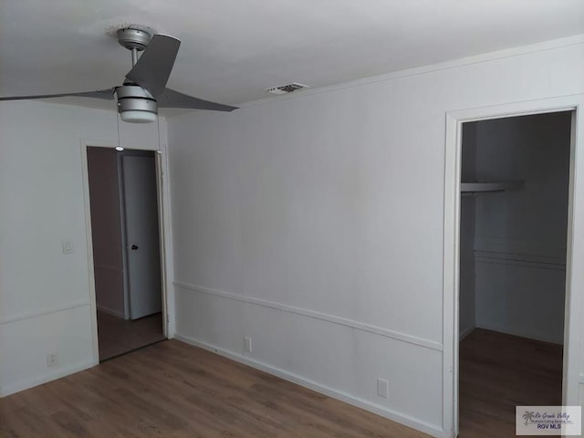 unfurnished bedroom featuring a walk in closet, ceiling fan, a closet, and hardwood / wood-style flooring