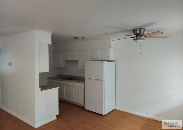 kitchen featuring ceiling fan, white fridge, light hardwood / wood-style floors, and sink